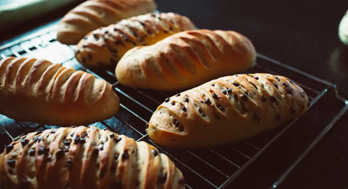 Local bakery bread with chocolate chips cooling on a wire rack in natural light.