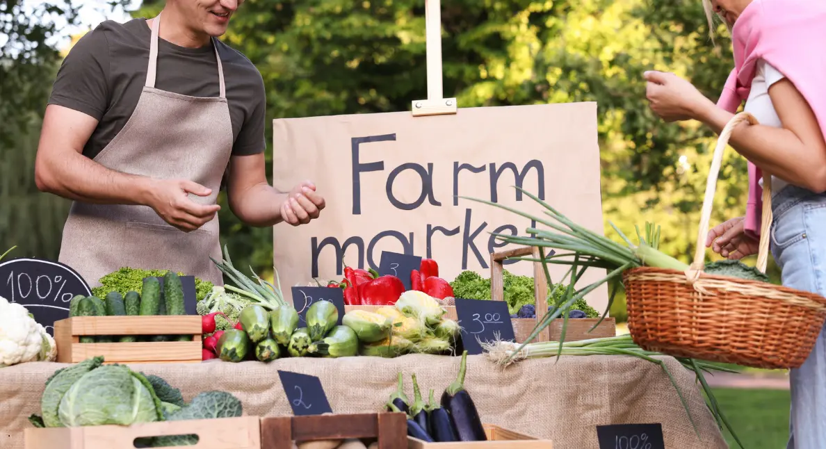 Local fruits and vegetables displayed on a rustic outdoor stand at a weekend farm market.