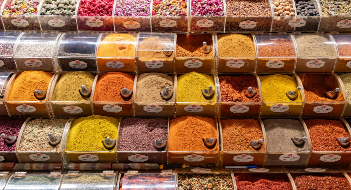 Shop local at a vibrant market stand displaying colorful spices in clear bulk containers.