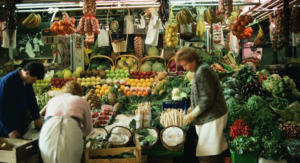 Support local farmers by shopping at a colorful produce stall staffed by market vendors and filled with fresh fruits and vegetables.