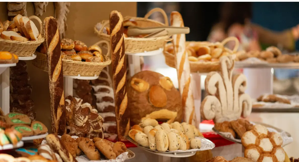 Fresh-baked pastries and creatively shaped breads arranged in a festive bakery showcase.