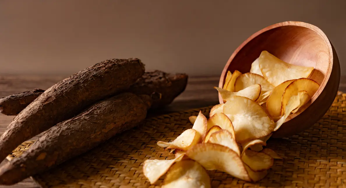 Local farm shops offering cassava and handmade cassava chips in a rustic wooden bowl on a woven mat.