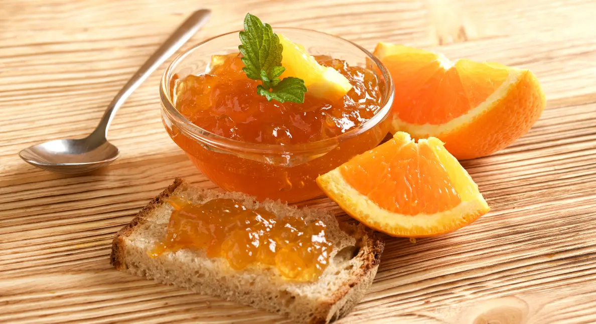 Small-batch jam made with fresh oranges served on rustic toast with citrus slices.
