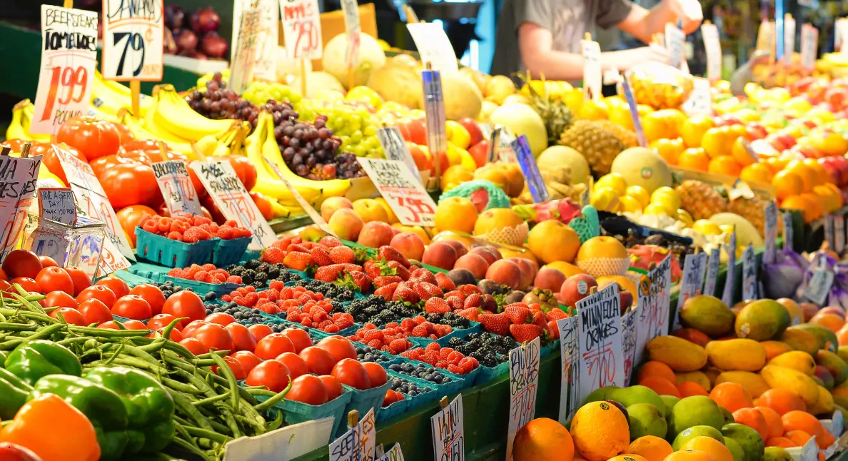 A vibrant market stall overflowing with tomatoes, berries, peaches, and tropical fruits, perfect for community-based shopping.