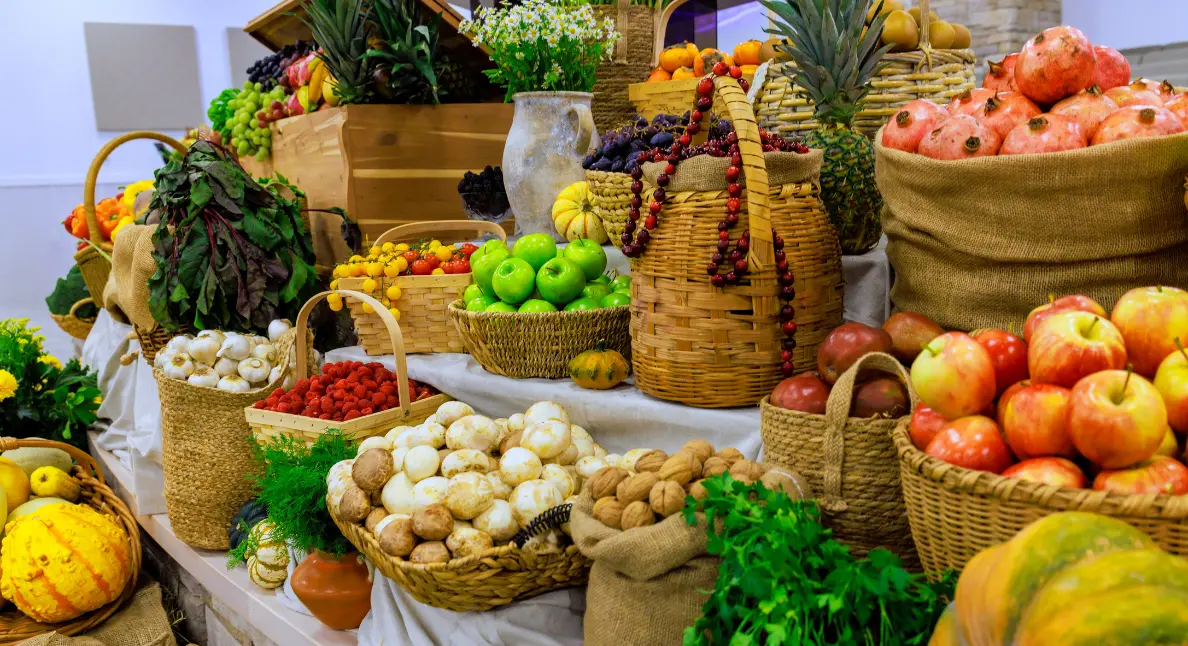 Wicker baskets and burlap sacks filled with apples, mushrooms, walnuts, pomegranates, and herbs showcase the abundance of local food sourcing.