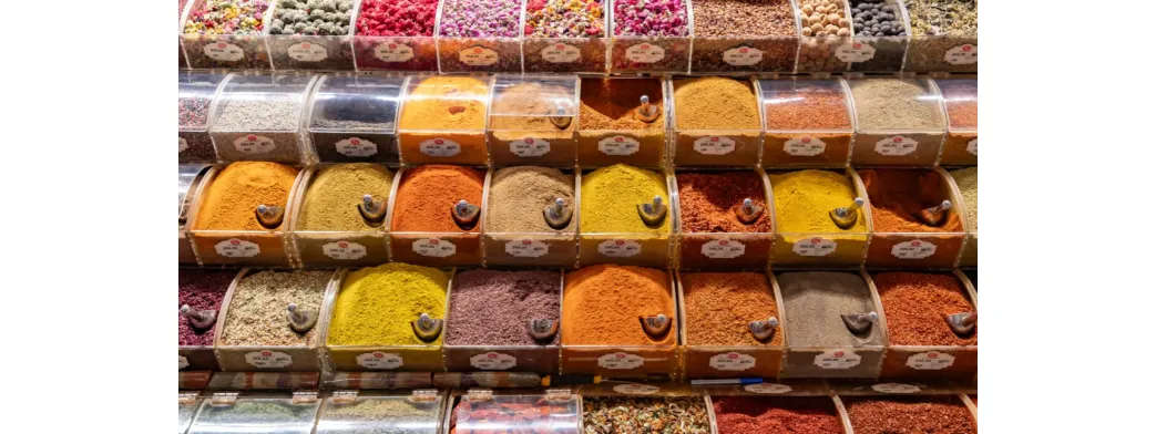 Shop local at a vibrant market stand displaying colorful spices in clear bulk containers.
