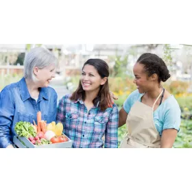 Local farmers sharing smiles while holding a box of fresh vegetables at a community market.