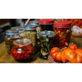Small businesses offering assorted pickled vegetables and preserves in jars alongside fresh tomatoes.