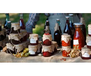 Artisanal goods displayed in glass jars and bottles at a rustic outdoor market stall.