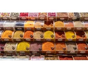 Shop local at a vibrant market stand displaying colorful spices in clear bulk containers.