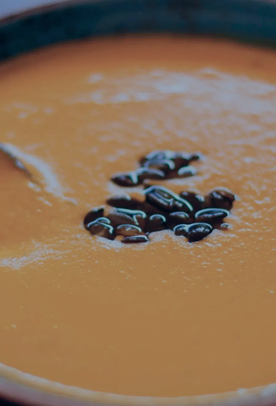 Cream soup in a bowl topped with black beans, served with a smooth, velvety texture.