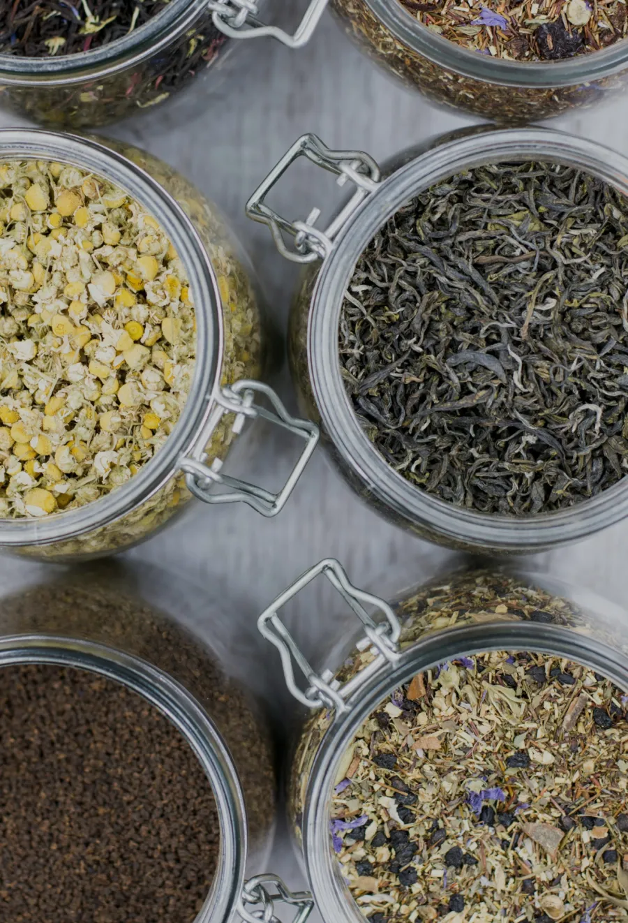 Artisan tea blends in glass jars, including chamomile, green tea, and mixed herbal varieties.