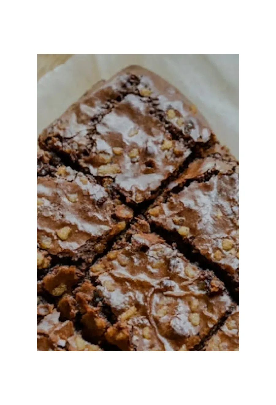 Brownie bars with chopped nuts are cut into squares and arranged on parchment paper.