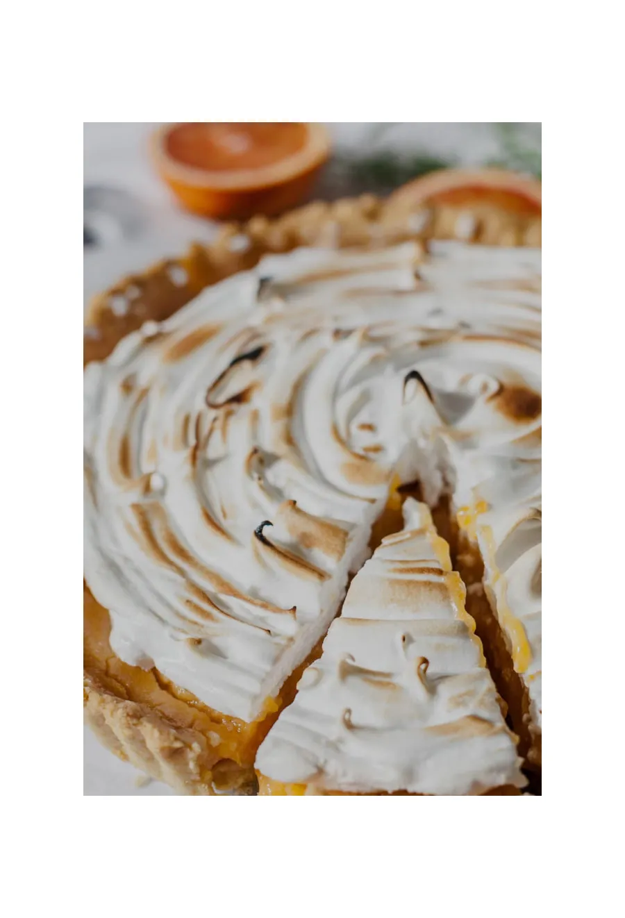 Baked goods like a citrus meringue pie are sliced to reveal a golden filling and toasted topping.