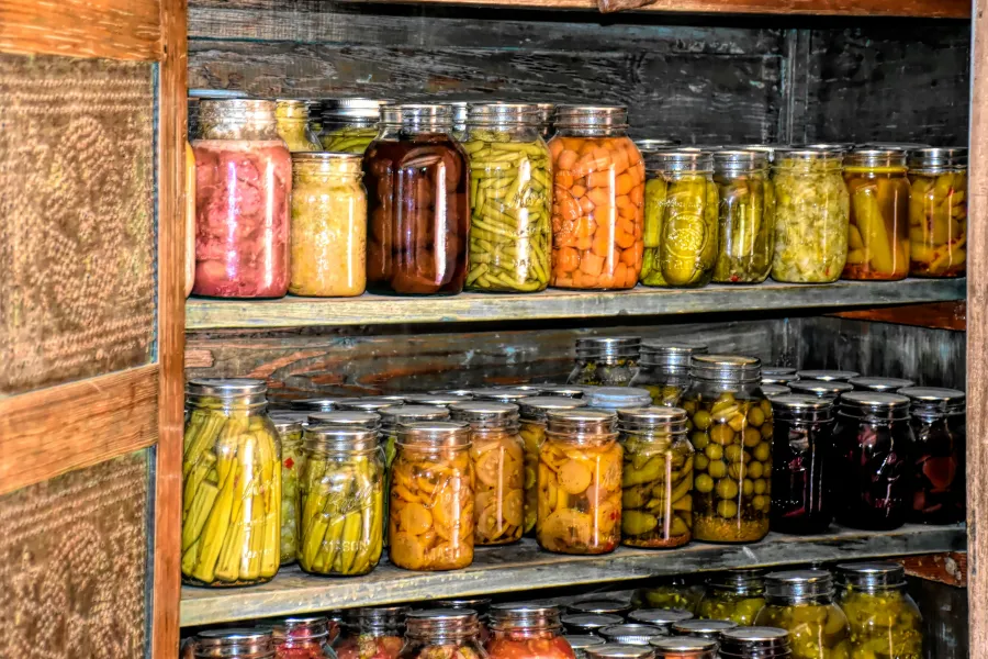 Pantry ingredients like pasta, legumes, and dried goods neatly stored in glass jars on a backlit shelf.